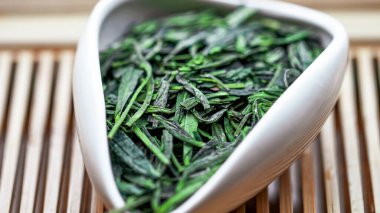 Çin yeşil çay kuyusu çay kabında bulanık arkaplanlı makro resim.