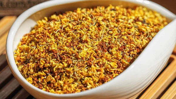 Çay kabında çay içmek için parlak, sarı osmanthus çiçekleri, bulanık arkaplan ile makro resim.