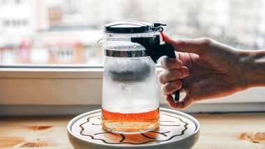 Çay demlerken ve boşaltma düğmesine basarken çay demlemek için düğmeli plastik cam çaydanlık..