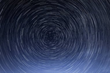 Stellar trails, the rotation of bright stars at night around the Polar Star against a blue sky and a meteor clipart