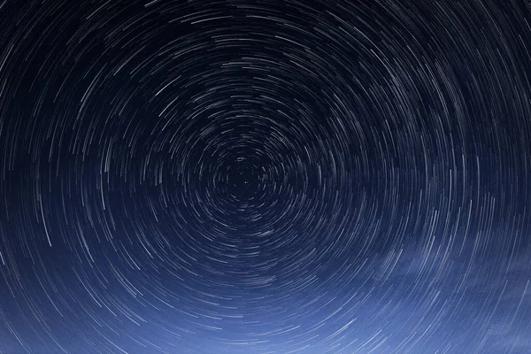 Stellar trails, the rotation of bright stars at night around the Polar Star against a blue sky