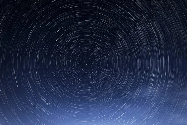 Stellar trails, the rotation of bright stars at night around the Polar Star against a blue sky — Stock Photo, Image