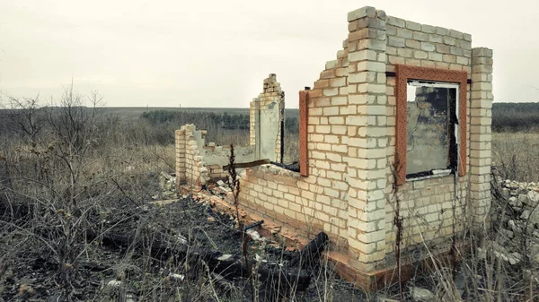 Structure en briques détruites et brûlées avec une fenêtre au bord du champ — Photo