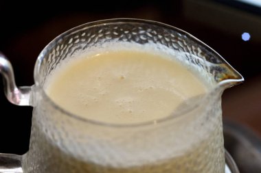 Cam bir kavanozda kaynamış süt, sapı ve borusu var.