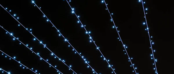 Líneas festivas brillantes de luces parpadeantes frías sobre un fondo negro — Foto de Stock