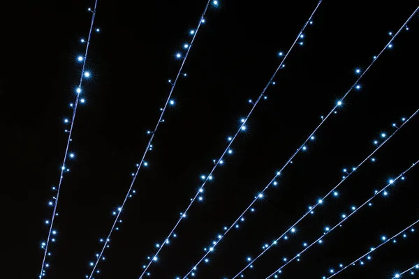 Líneas festivas brillantes de luces parpadeantes frías sobre un fondo negro — Foto de Stock