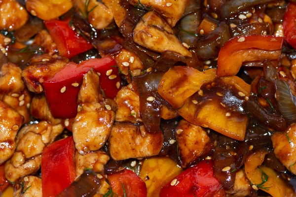 Braised chicken with onion, sweet pepper and sesame seeds in a dark sauce. — Stock Photo, Image