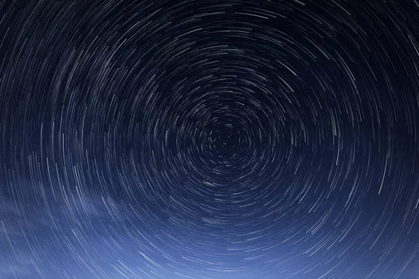 Gwiezdne szlaki, obrót jasnych gwiazd w nocy wokół Gwiazdy Polarnej przeciwko błękitnemu niebu — Zdjęcie stockowe