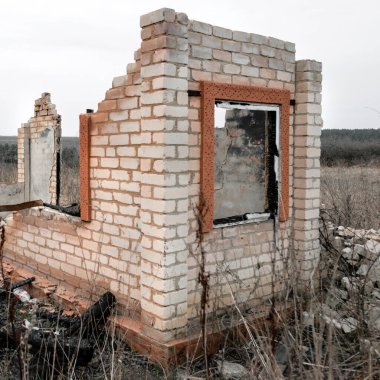 Yıkılmış ve yanmış tuğla yapı. Alanın kenarında bir pencere var.
