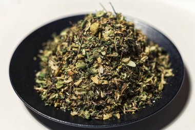 Kurumuş otlar, beyaz arka planda siyah bir tabakta yatıştırıcı bitkiler.