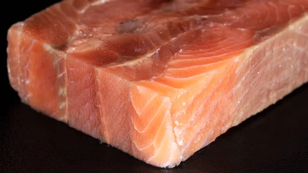 Würfelstück roher rosa Lachsfisch auf schwarzem Hintergrund — Stockfoto