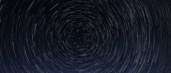 Senderos estelares, la rotación de estrellas brillantes en la noche alrededor de la Estrella Polar contra un cielo azul y un meteorito — Foto de Stock