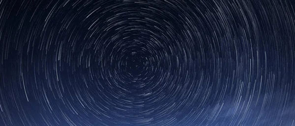 Stellar trails, the rotation of bright stars at night around the Polar Star against a blue sky — Stock Photo, Image