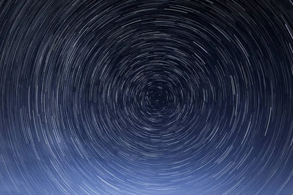 Stellaire paden, de rotatie van heldere sterren 's nachts rond de Poolster tegen een blauwe hemel en een meteoor — Stockfoto