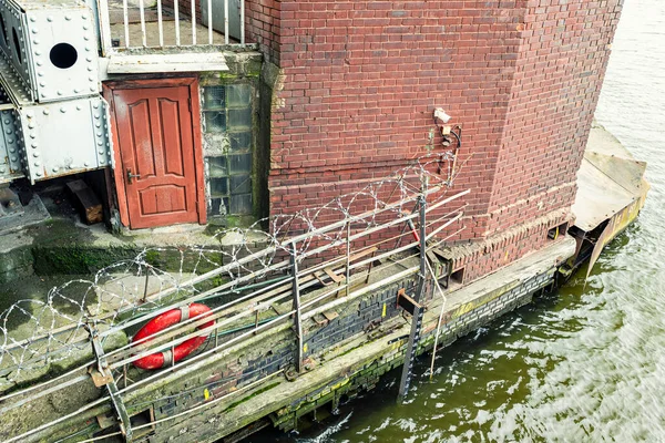 Tür in altem Backsteinbau am Fluss, roter Rettungsring — Stockfoto