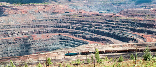 Iron ore extraction in the quarry of the Mikhailovsky mining and processing plant, a train travels inside the quarry
