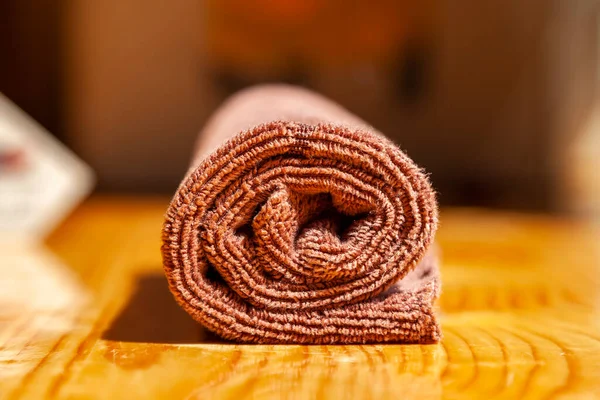 Kahverengi üç katlı mikrofiber çay havlusu ahşap bir yüzeye sarılmış.