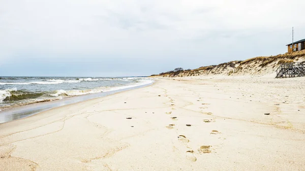 Fale morskie i ślady stóp na piasku na plaży i zachmurzone niebo — Zdjęcie stockowe