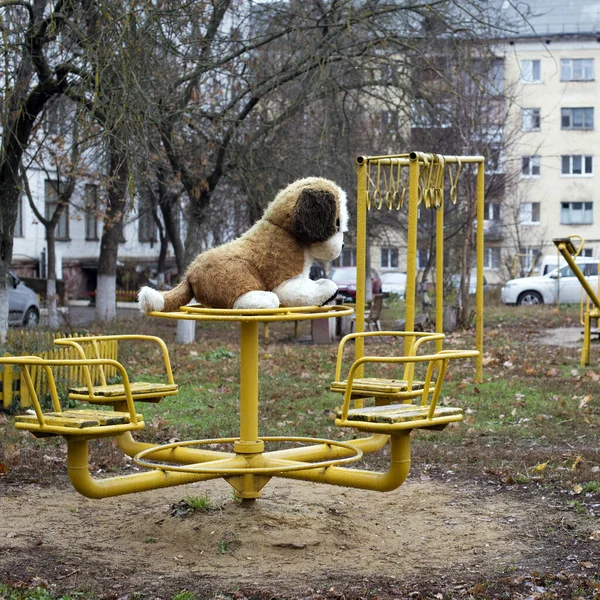 ロシアの庭の金属製のスイングで大きな柔らかいおもちゃの犬 — ストック写真