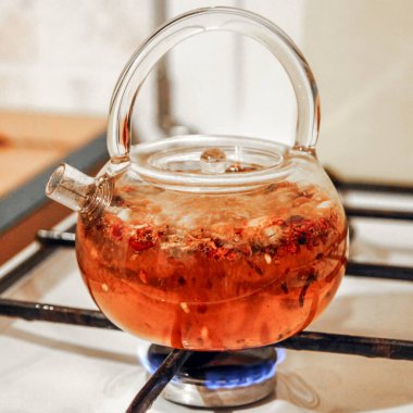Kırmızı çay içeceği, gaz ocağında cam bir çaydanlıkta kaynatılır. Yakın plan.