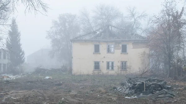 Заброшенный двухэтажный деревянный дом на дороге в туманный день — стоковое фото