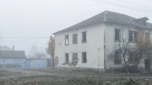 Закинутий двоповерховий дерев'яний будинок біля дороги в туманний день — стокове фото