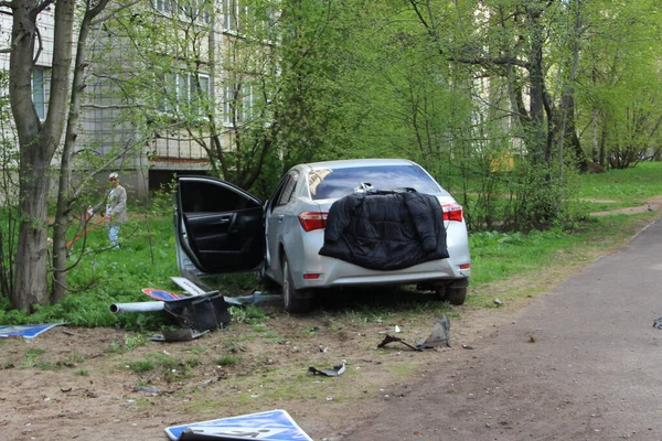 Auto-ongeluk. Een gebroken grijze auto aan de kant van de weg met een open deur. Verkeersongeval en wrakstukken op de grond en op het gras. — Stockfoto