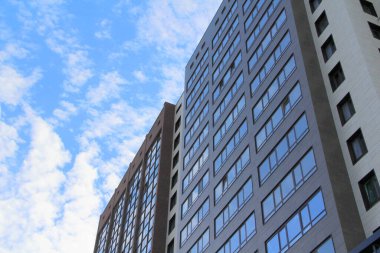 Gökyüzüne bakan pencereleri olan çok katlı bir binanın duvarı. Modern bir gökdelendeki plastik pencereler. Alt manzara. Web ve baskı için stok fotoğrafı modern kentsel gelişim.