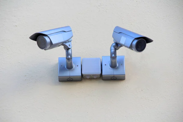 家のレンガの壁に取り付けられた2つの銀監視カメラ セキュリティコンセプト 追跡システム 監視と制御 テキストのための空のスペースでウェブと印刷のための写真 — ストック写真