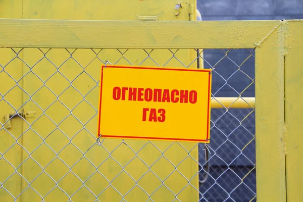ガス設備を囲む金属メッシュ製の柵の上に 火のガス を読み取る黄色のプラーク ガス供給 安全の概念 — ストック写真