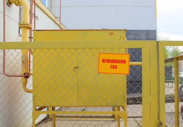 ガス設備を囲む金属メッシュ製の柵の上に 火のガス を読み取る黄色のプラーク ガス供給 安全の概念 — ストック写真