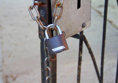 Parlak kavisli yeni bir kahverengi asma kilit demir bir kapının zincirinde asılı..