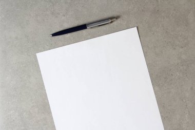 Açık gri beton arka planda tükenmez kalemle beyaz kağıt şablonu. Yeni fikir, iş planı ve strateji kavramı, içeriğin geliştirilmesi ve uygulanması. Metin için boş alanı olan stok fotoğrafı.