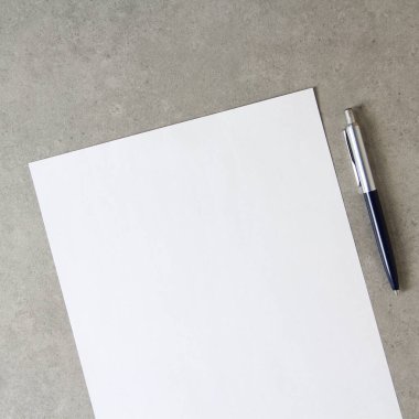 Açık gri beton arka planda tükenmez kalemle beyaz kağıt şablonu. Yeni fikir, iş planı ve strateji kavramı, içeriğin geliştirilmesi ve uygulanması. Metin için boş alanı olan stok fotoğrafı.