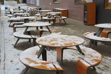 Masalar ve banklar, Rusya 'daki McDonald' s restoranının yanındaki kaldırımda kar tezgahıyla kaplı..