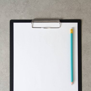 Beyaz kağıt şablonu, açık gri beton arka planda, siyah bir tablette, klipsli, basit bir kalemle. Yeni fikir, iş planı ve strateji kavramı, içeriğin geliştirilmesi ve uygulanması. Metin için boş alanı olan stok fotoğrafı.