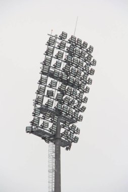 Metal direkli stadyum ışıkları, ışık direği, spor stadyumunda beyaz gökyüzüne karşı projektörlü kule.