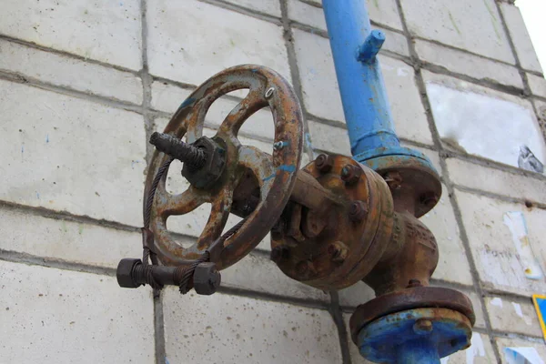 Old damaged and rusty iron oil pipe valve wheel. Metal, pipeline and mechanic concept. An old iron valve on a gas pipe. A valve to cover the pipe with a round handle.