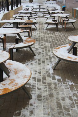 Masalar ve banklar karla kaplı şehir caddesinde bir kaldırımda Rusya 'da kış mevsiminin yanındaki restoranın yanında..