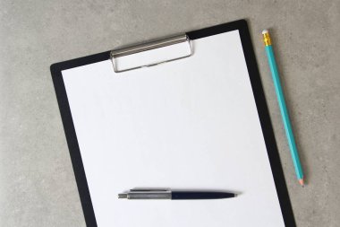 Tükenmez kalemle beyaz kağıt şablonu ve siyah bir tabletle açık gri beton arka planda basit bir kalem. Yeni fikir, iş planı ve strateji kavramı, içeriğin geliştirilmesi ve uygulanması. Boş boşluklu fotoğraf yükle