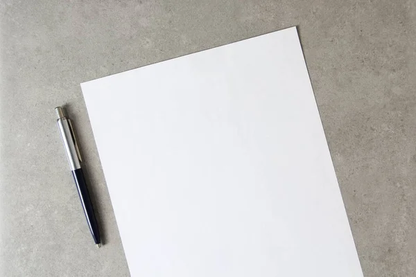 Template of white paper with a ballpoint pen on light grey concrete background. Concept of new idea, business plan and strategy, development and implementation of content. Stock photo with empty space for text.