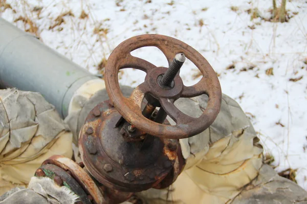 Old damaged and rusty iron oil pipe valve wheel. Metal, pipeline and mechanic concept. An old iron valve on a gas pipe. A valve to cover the pipe with a round handle.