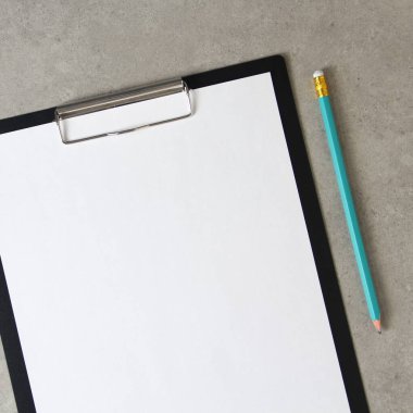 Beyaz kağıt şablonu, açık gri beton arka planda, siyah bir tablette, klipsli, basit bir kalemle. Yeni fikir, iş planı ve strateji kavramı, içeriğin geliştirilmesi ve uygulanması. Metin için boş alanı olan stok fotoğrafı.