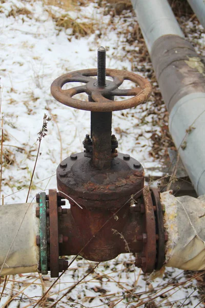 Old damaged and rusty iron oil pipe valve wheel. Metal, pipeline and mechanic concept. An old iron valve on a gas pipe. A valve to cover the pipe with a round handle.