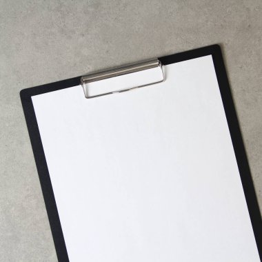 Açık gri beton arka plan üzerine beyaz kağıt şablonu siyah bir tablette şarjörlü. Yeni fikir, iş planı ve strateji kavramı, içeriğin geliştirilmesi ve uygulanması. Metin için boş alanı olan stok fotoğrafı.