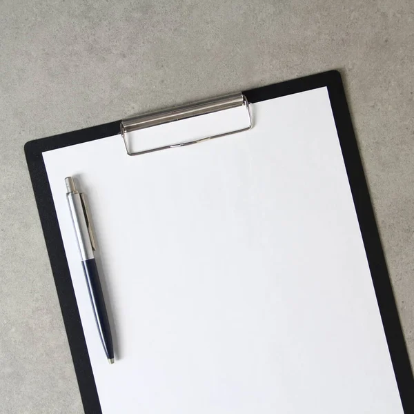 Beyaz kağıt şablonu açık gri arka plan üzerinde tükenmez kalemle siyah bir tablet içinde şarjörlü. Yeni fikir, iş planı ve strateji kavramı, içeriğin geliştirilmesi ve uygulanması. Metin için boş alanı olan stok fotoğrafı.