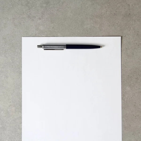 Modelo de papel branco com uma caneta esferográfica sobre fundo de concreto cinza claro. Conceito de nova ideia, plano de negócios e estratégia, desenvolvimento e implementação de conteúdo. Foto stock com espaço vazio — Fotografia de Stock