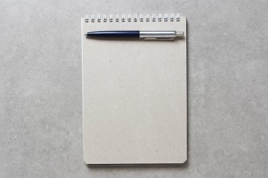 Açık gri beton arkaplanlı tükenmez kalemle kaplı bir el işi kâğıdı olan bir yay defteri. Yeni fikir, iş planı ve strateji kavramı, içeriğin geliştirilmesi ve uygulanması