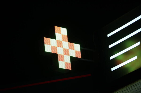 Светящийся пиксельный крест светодиодных ламп на черном фоне. Крест с рисунком в белый и оранжевый квадратный символ здоровья, медицины, самообслуживания. Склад фото с пустым пространством для текста и дизайна.