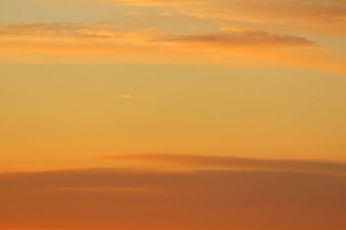 Ufkun altında güneş ve gün batımında veya şafakta güneşin aydınlattığı ateşli turuncu gökyüzünde bulutlar. Metin ve tasarım için yer.